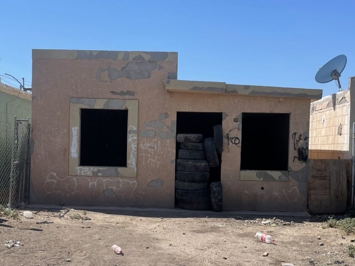 Antes: casa vandalizada con grafiti, sin puerta ni ventanas y llantas apiladas en la entrada